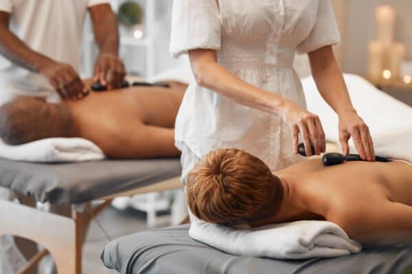 Hot stone massage, black couple and relax spa in skincare wellness, healthcare or stress management