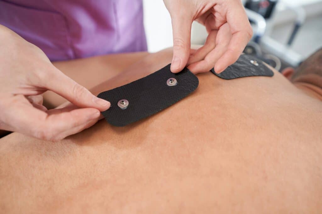 Doctor hands placing myostimulation electro pads on male back