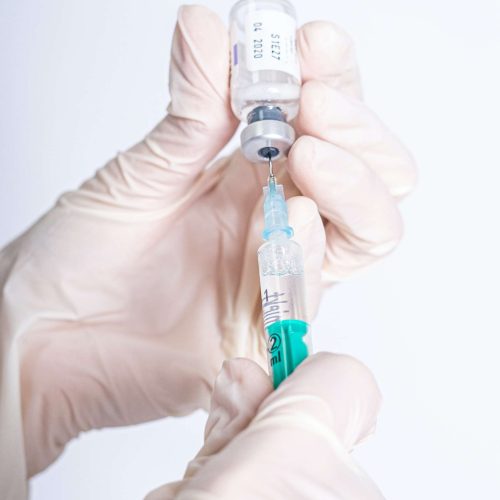 Selective focus shot of a hand holding an injection syringe with peptides