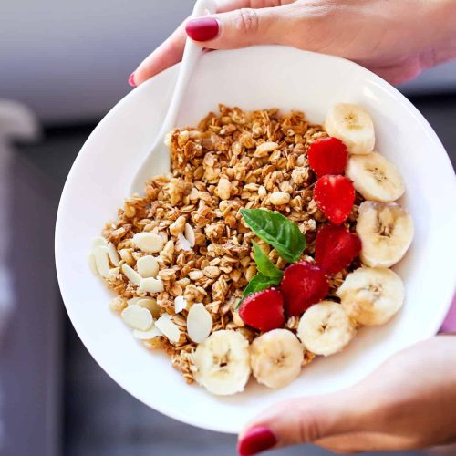 Woman eating healthy breakfast bowl, hold in hand